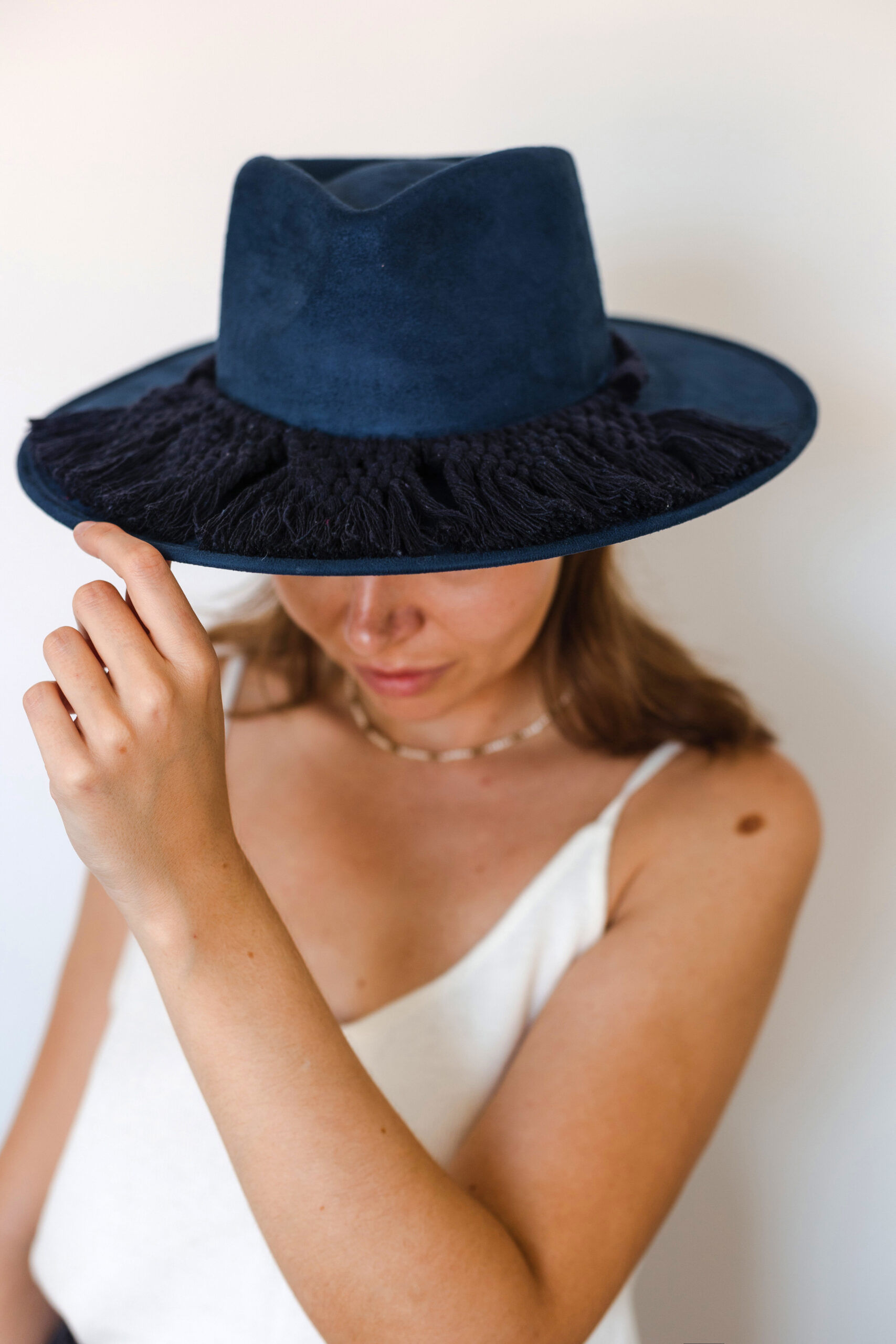 A dark blue colored hat made in Mexico made from synthetic suede back with a dark blue colored macrame hat accessory