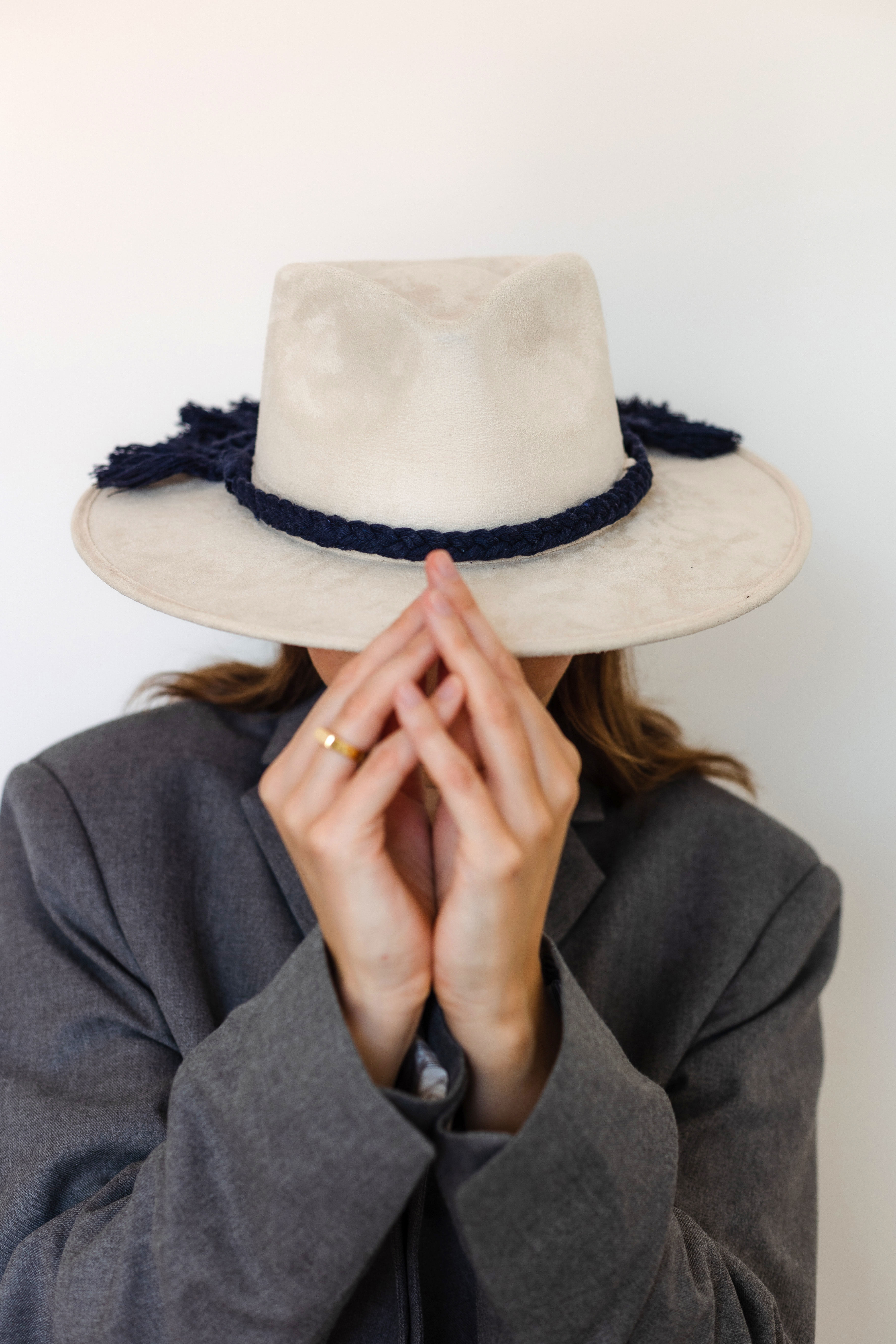 A cream colored hat made in Mexico, made from synthetic suede with macrame hat accessory in dark blue