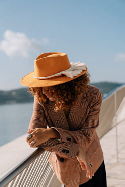 A yellow colored hat made in Mexico made from synthetic suede with an ivory colored macrame hat accessory